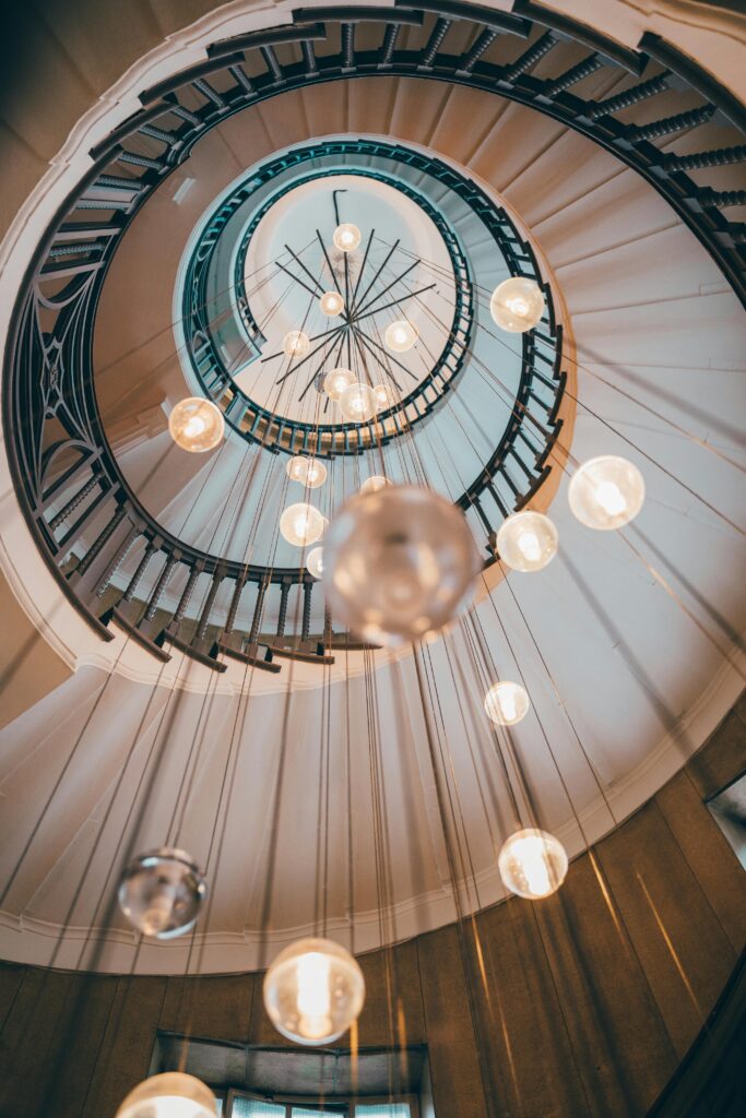 Stunning low angle view of a spiral staircase with elegant hanging lights in London.